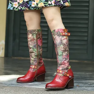 Bottes vintage en cuir rouge avec tige à fleurs et boucles décoratives de profil.