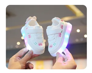 Gros plan de baskets LED blanches pour tout-petits avec motif d'ours rose et smiley