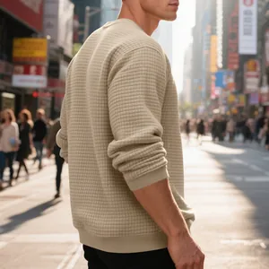Detail view of men's beige waffle knit sweatshirt texture in urban street setting