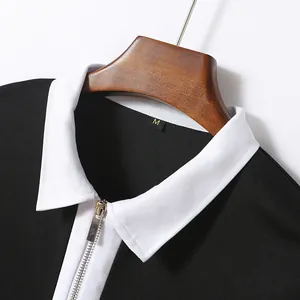 Close-up detail showing the white collar and metallic half-zip on a black long-sleeve polo shirt