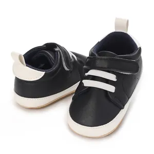 Detail view of black infant boy casual sneakers with white soles and hook-and-loop closure.