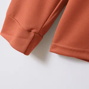 Close-up detail of rust-orange men's polo shirt showing cuff and hem fabric texture.