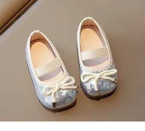 Top-down view of silver sequined girl's flat shoes with white bows and elastic bands