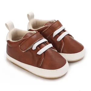 Close-up of brown faux leather baby sneakers with white laces and soft soles