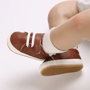 Detail view of brown faux leather baby boy sneakers with white laces and Velcro strap