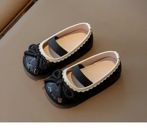 Close-up of girls' black princess shoes with sparkly sequins and decorative bows.