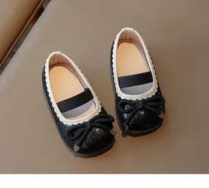 Close-up of black sequined girl's Mary Jane shoes with bow and white scallop trim detail.