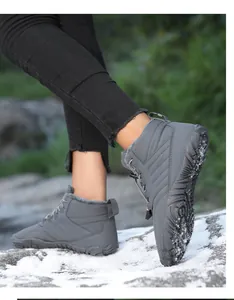 Close-up of gray mid-top fleece-lined snow boots worn on a snowy rock outdoor scene