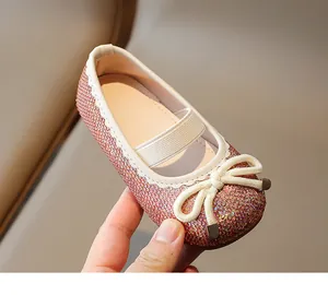 Close-up detail of girl's pink sequined princess shoes with cream bow and elastic strap