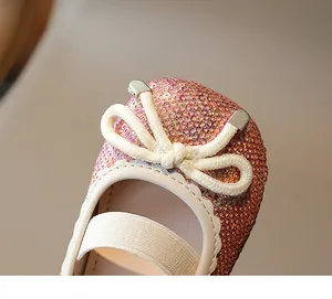 Close-up detail of girls' sparkling sequin princess shoes with cream bow ornament