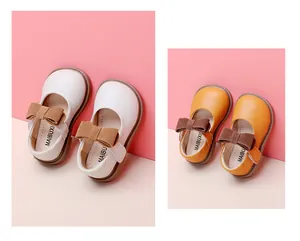 Macro view of baby girl princess shoes in cream and yellow colors with brown bow accents.