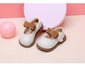 Close-up detail of white baby girl Mary Jane shoes with brown bow decorations