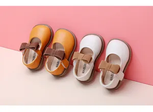 Detail view of baby girl soft leather princess shoes with bows in white and orange