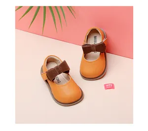 Close-up view of orange leather baby girl princess shoes with soft brown bow detail