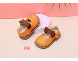 Toddler girl's orange soft leather Mary Jane shoes with brown bows on a display stand