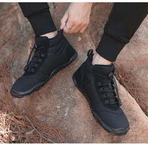 Close-up detail of men's warm black outdoor winter boots worn on rocky terrain