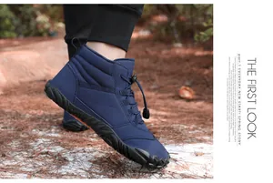Detailed view of blue winter outdoor boots with non-slip soles in a forest setting.