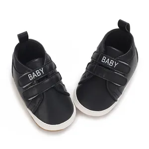 Nahaufnahme von schwarzen Babyschuhen mit 'BABY' Klettverschluss und weißer weicher Sohle