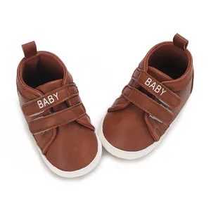 Nahaufnahme von braunen Babyschuhen mit Klettverschluss und BABY-Aufdruck für Neugeborene