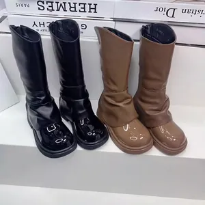 Λεπτομερής προβολή των μαύρων και καφέ δερμάτινων μπότων για κορίτσια με μοναδικό σχέδιο