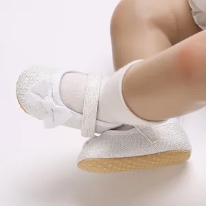 Detaillierte Nahaufnahme weißer Lauflernschuhe für Babymädchen mit Schleife und weicher Sohle
