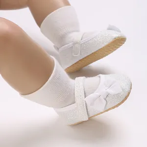 Nahaufnahme von weißen Glitzer-Babyschuhen für Mädchen mit Schleife und weicher Sohle