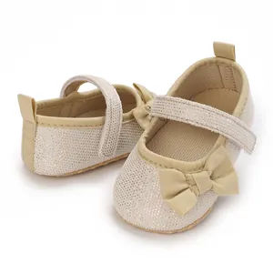 Detailansicht glitzernder beiger Baby-Prinzessinnenschuhe mit Satinschleife und Riemen.