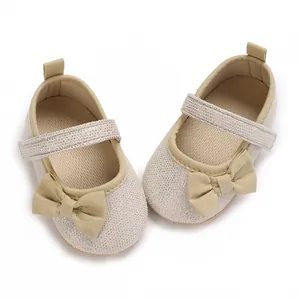 Draufsicht auf glitzernde cremefarbene Baby-Prinzessinnenschuhe mit weicher Schleife