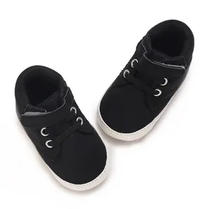 Detailansicht schwarzer Babyschuhe mit weicher weißer Sohle und Klettverschluss.