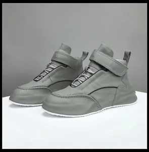 Vista lateral de zapatillas altas de cuero gris con suela blanca gruesa y velcro.
