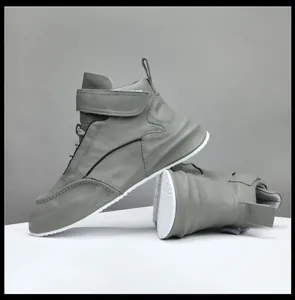 Detalle lateral de zapatillas altas de cuero gris para hombre con suelas blancas gruesas.
