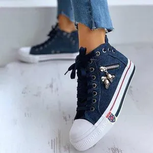 Close-up detail of women's denim high-top canvas shoes featuring side zipper and skull charms