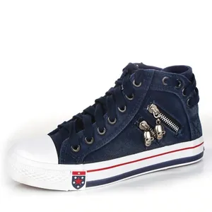Close-up detail of navy blue denim high-top canvas shoe with unique skull charms and side zipper