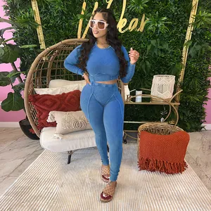 Model wearing blue ribbed long sleeve crop top and matching leggings in cozy indoor setting