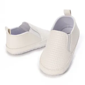 Primer plano de zapatos blancos para bebé con textura tejida y paneles laterales elásticos