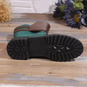 Detailed view of the durable non-slip black rubber sole on a green and brown knight boot
