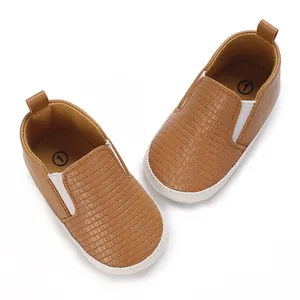 Vista superior de zapatos de bebé marrones con textura tejida y paneles elásticos blancos
