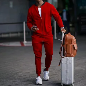 Ανδρική κόκκινη αθλητική φόρμα δύο τεμαχίων με ζακέτα και παντελόνι σε περιβάλλον αεροδρομίου.