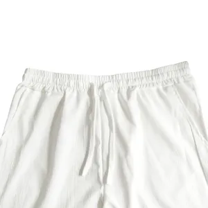 Detailweergave van witte linnen herenbroek met elastische taille en trekkoord.