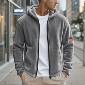 Gros plan sur un sweat à capuche en polaire grise avec texture et écusson drapeau