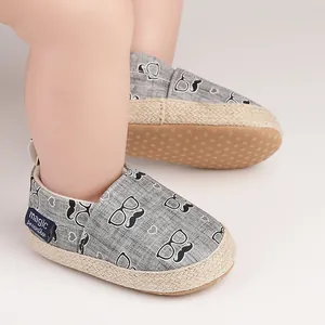 Détail rapproché de chaussures de marche pour bébé grises avec imprimés moustaches et lunettes