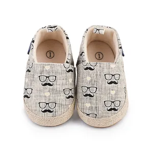 Détail de chaussures de marche pour bébé avec motifs moustaches et lunettes