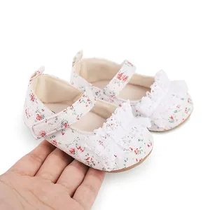 Close-up macro view of floral baby walking shoes with white lace ruffles held by hand