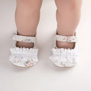 Detailed view of white lace baby walking shoes featuring floral print and ruffled trim.