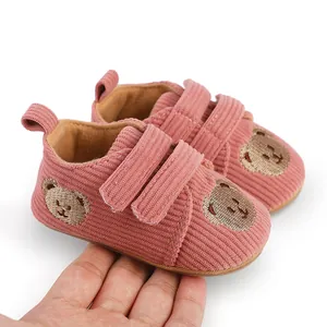 Detailansicht der rosa Baby-Lauflernschuhe aus Cord mit süßem Bären-Stickdesign.