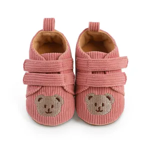 Detail der rosa Cord-Lauflernschuhe für Babys mit süßem besticktem Bärengesicht.