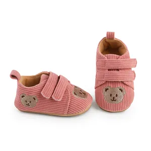 Detaillierte Seitenansicht rosa Baby-Lauflernschuhe aus Cord mit süßer Bärenstickerei.