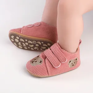 Nahaufnahme von rosa Baby-Lauflernschuhen aus Cord mit einer süßen Bärenstickerei