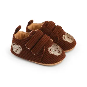 Detaillierte Nahaufnahme der braunen Baby-Lauflernschuhe aus Cord mit Bärenstickerei