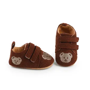 Nahaufnahme von braunen Baby-Lauflernschuhen aus Cord mit süßer Bärenstickerei und Klett.